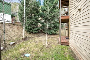 Ein Wohngarten mit Holzdeck, einer kleinen Veranda und einem Metallzaun.