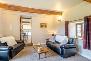 A living room with two black leather sofas, a wooden coffee table, and a painting on the wall. - 2 Bed in Gilsland (oc-o45731) (Waterhead)