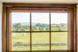 A window with a view of a rural landscape, including fields, trees, and a stone wall. - 2 Bed in Gilsland (oc-o45731) (Waterhead)