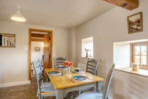 A dining area with a wooden table, chairs, and a vase of flowers. - 2 Bed in Gilsland (oc-o45731) (Waterhead)