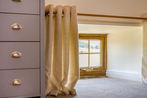 Een kamer met een raam, een houten vloer en een grijze dressoir met lades.
