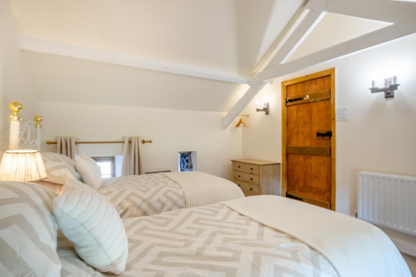 A bedroom with a bed, bedside table, lamp, and a wooden wardrobe.