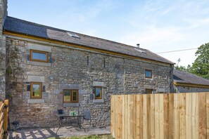 A stone building with a wooden fence, a table with chairs, and a clear sky. - 2 Bed in Gilsland (oc-o45731) (Waterhead)