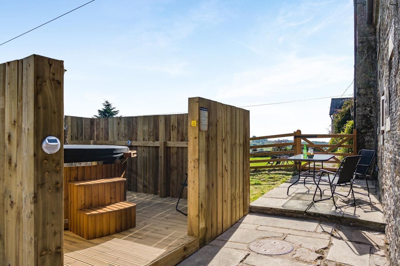 A wooden outdoor seating area with a grill and a table with chairs.