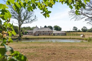 A rural property with a stone building, a fenced paddock, and a small water body. - 2 Bed in St. Giles (oc-c45183) (Saint Giles in the Wood)