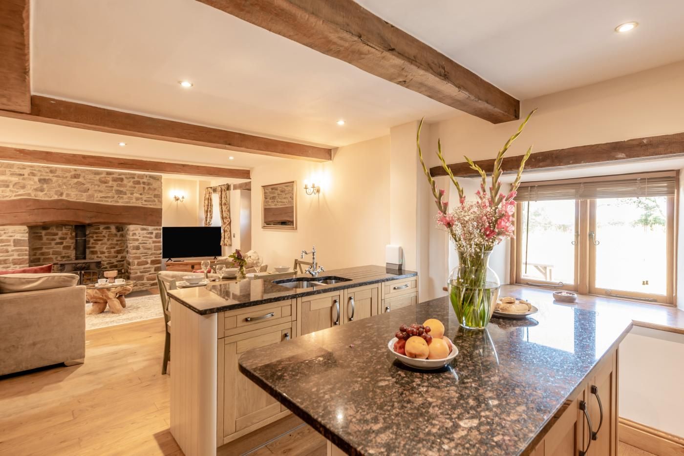 A modern kitchen with a large island, stone fireplace, and a dining area with a sofa.