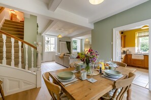 A dining area with a wooden table set for four, surrounded by chairs. A staircase with white balusters leads to an upper floor. - 2 Bed in Gargrave (oc-k45568) (Gargrave)