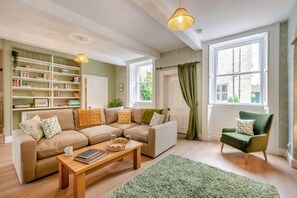 A living room with a sofa, armchair, coffee table, bookshelf, and large windows with curtains. - 2 Bed in Gargrave (oc-k45568) (Gargrave)
