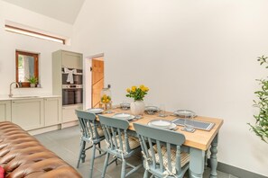 A dining area with a wooden table set for four, surrounded by blue chairs with checkered cushions. - 3 Bed in Challacombe (oc-s45342) (Challacombe)