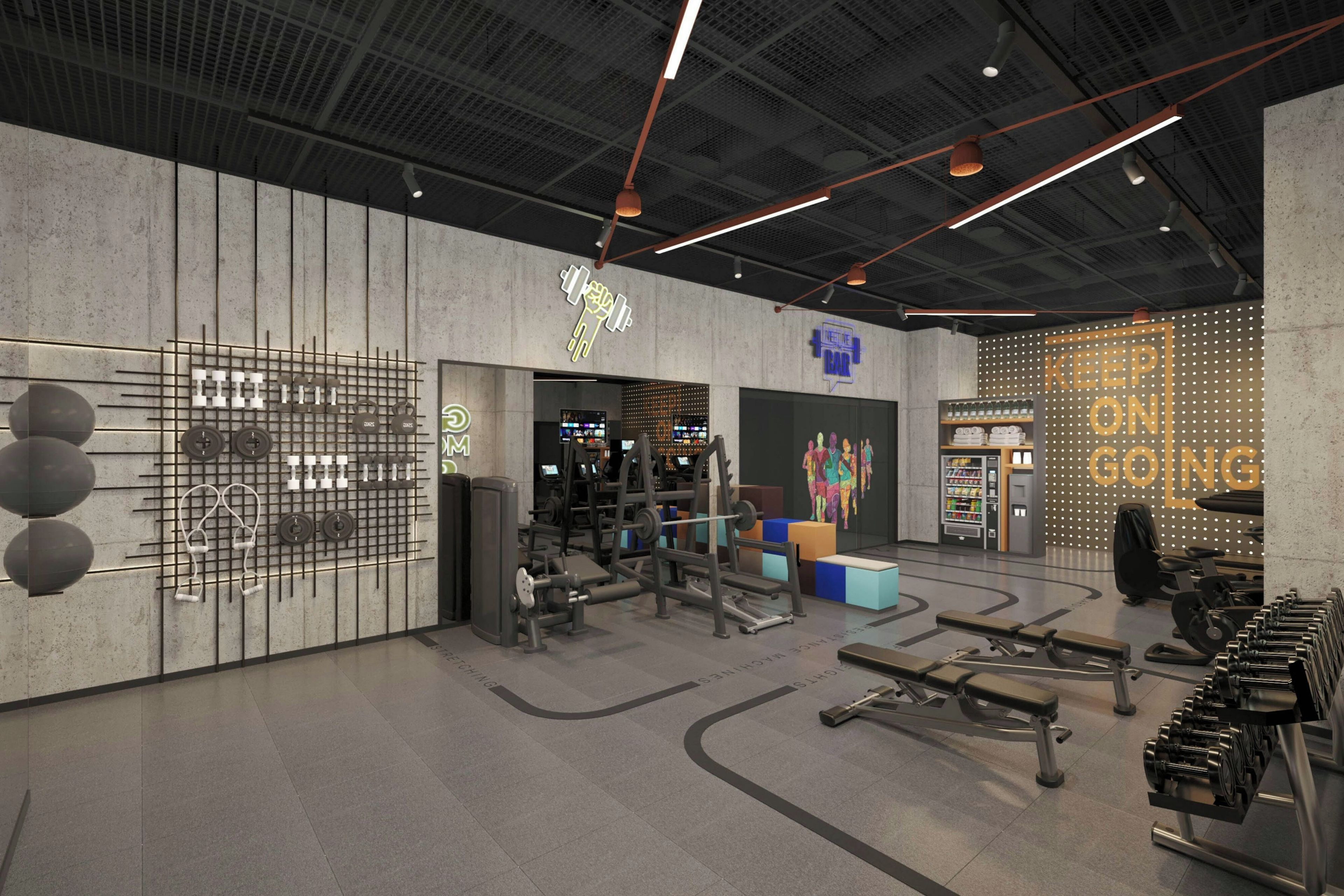 Un gimnasio moderno con diversos equipos de ejercicio, una zona de bar y una máquina expendedora.