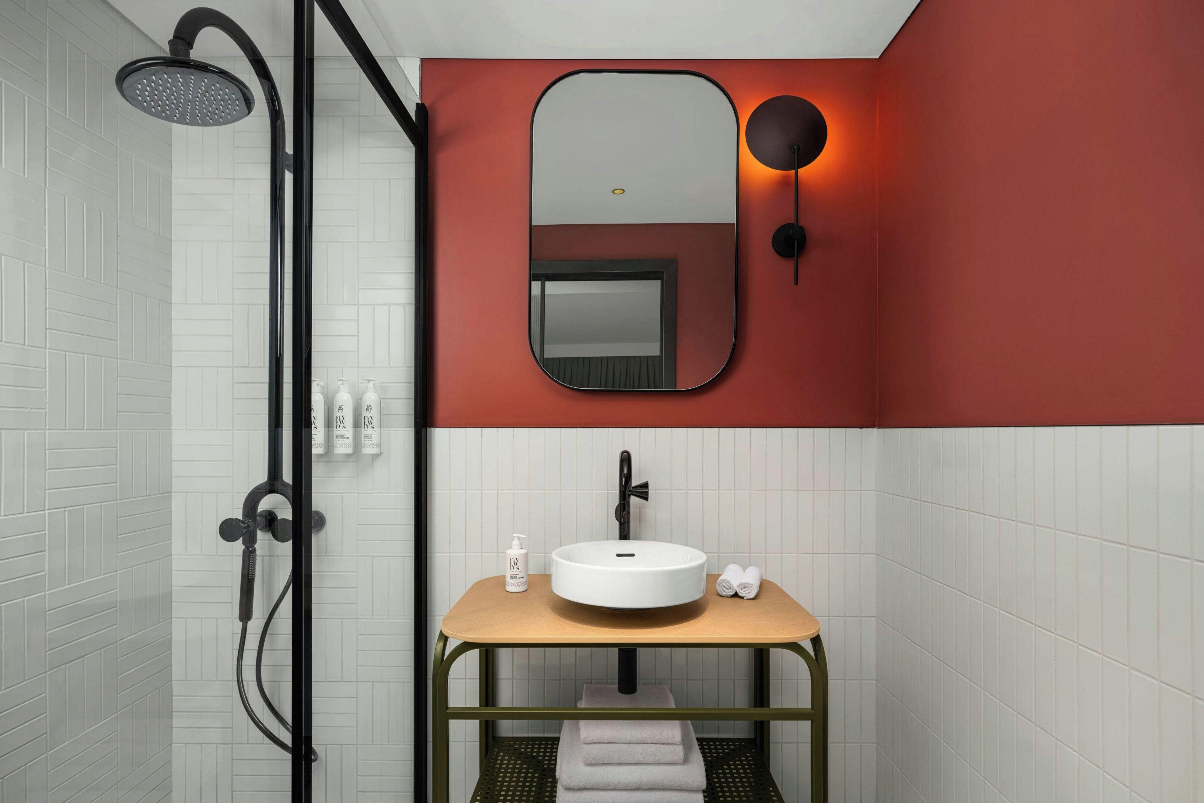 A bathroom with a shower, a sink with a mirror above it, and toiletries on the wall.