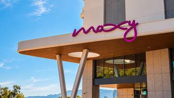 A modern building with a prominent 'mozy' sign, a car parked in front, and a clear sky.