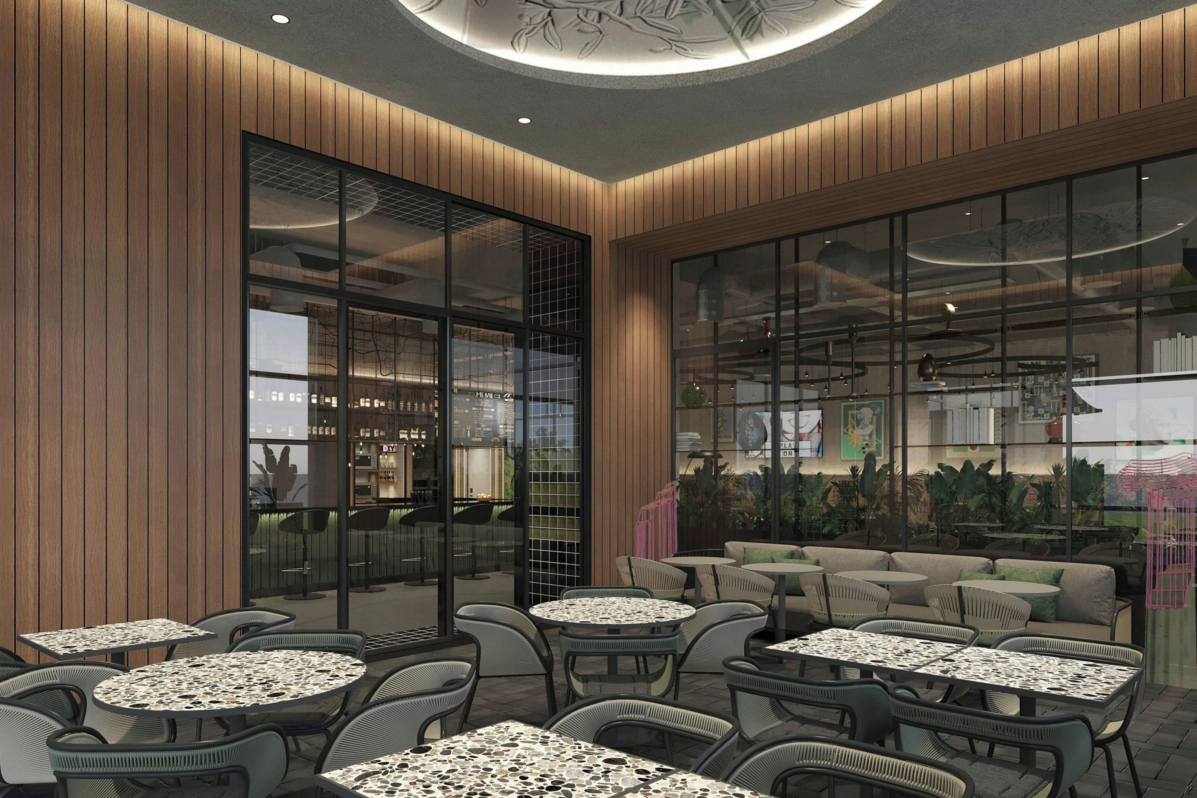 An indoor cafe with round tables and chairs, wooden panel walls, and a large window with a view of the city.