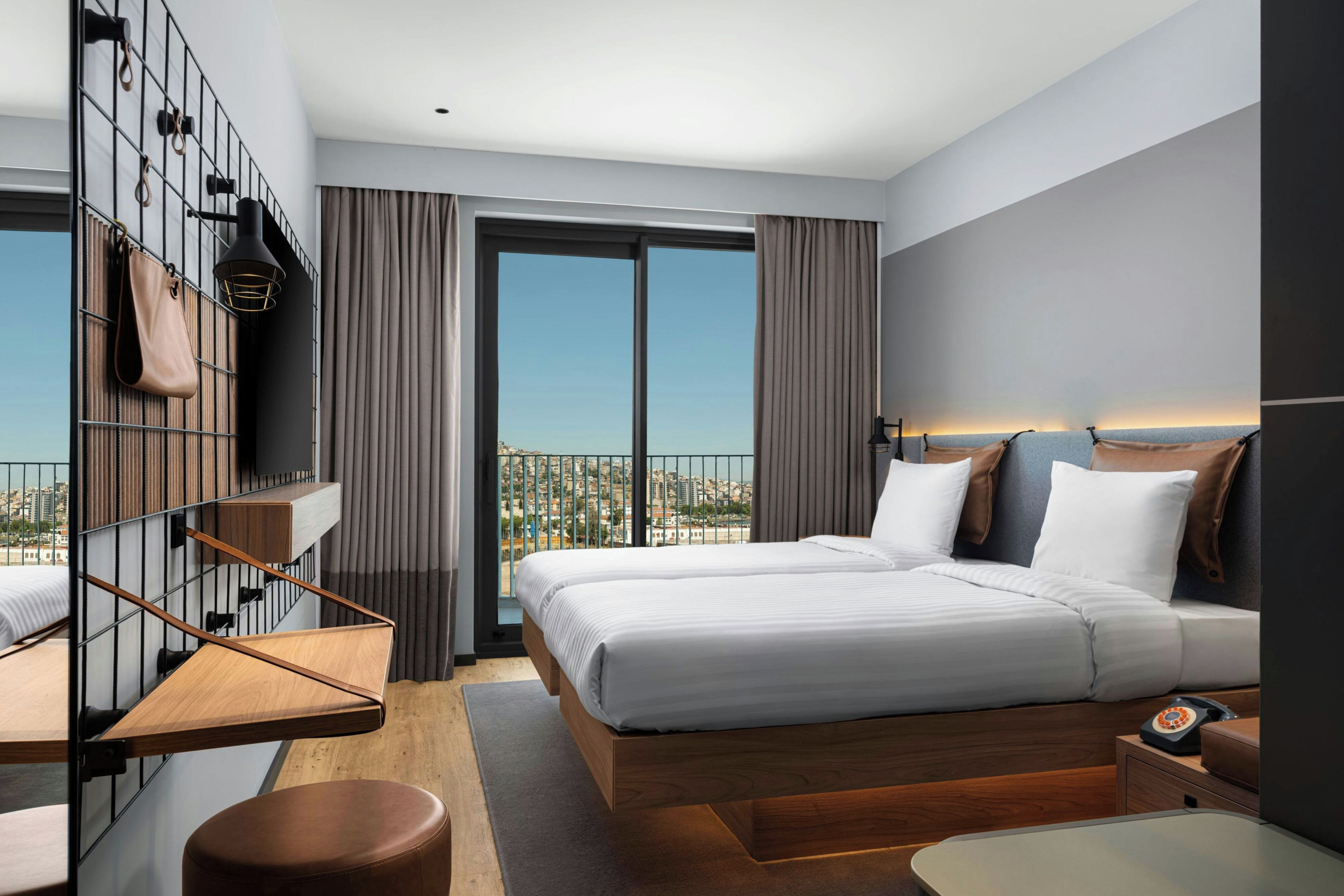 Une chambre d’hôtel moderne dotée d’un grand lit, d’un bureau, d’une chaise, d’une télévision et d’un balcon offrant une vue sur la ville.