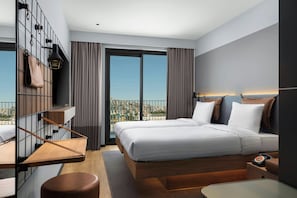 A modern hotel room with a large bed, a desk, a chair, a TV, and a balcony with a city view.