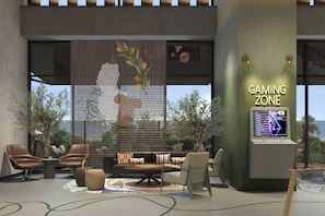 A gaming zone with a large screen, seating area, and a decorative wall. - Moxy Izmir (İzmir)