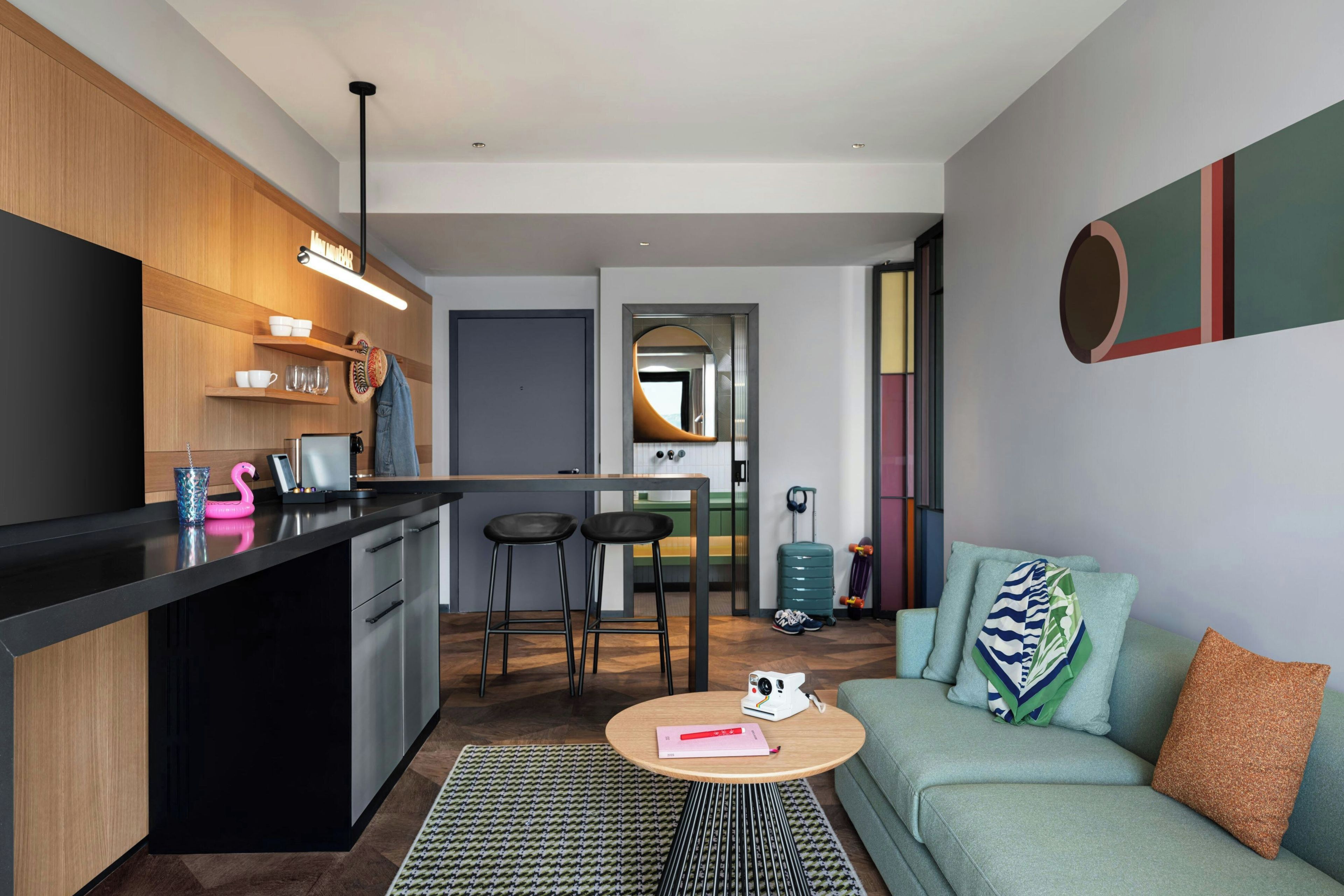 Un espacio habitable compacto con kitchenette, comedor y zona de estar.