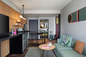 A compact living space with a kitchenette, a dining area, and a seating area. - Moxy Izmir (İzmir)