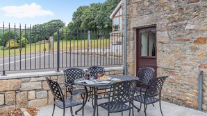 An outdoor patio with a stone wall, a metal fence, and a table with chairs. - 3 Bed in Tremar Coombe (oc-g45783) (Tremar)