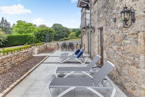 A stone building with a patio area featuring sun loungers and a table. - 3 Bed in Tremar Coombe (oc-g45783) (Tremar)