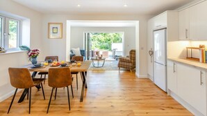 Een moderne keuken met houten vloeren, witte kasten en een eethoek met een tafel gedekt voor twee personen.