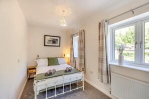 A bedroom with a bed, bedside table, lamp, window with curtains, radiator, and a hanging light fixture. - 2 Bed in Oreton (oc-h44970) (Oreton)