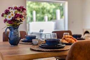 A dining table with a vase of flowers, bowls, plates, and a croissant. - 2 Bed in Oreton (oc-h44970) (Oreton)