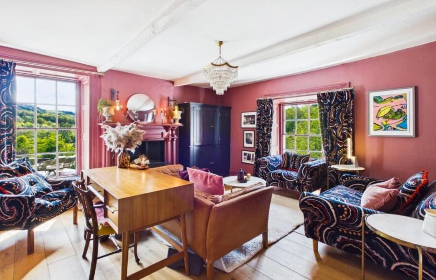 A room with a dining table, chairs, a sofa, and a patterned armchair.
