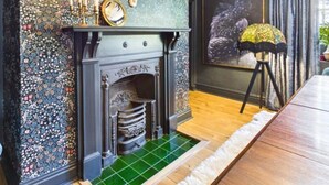 A room with a fireplace, patterned wallpaper, a deer head decoration, and a framed artwork on the wall. - 4 Bed in Marple (oc-45774) (Marple)