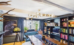 Ein gemütliches Wohnzimmer mit einem blauen Sofa, einem Holztisch und einem Bücherregal voller Bücher.
