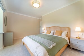 A bedroom with a bed, bedside lamps, a nightstand, a dresser, and a wall-mounted mirror. - 2 Bed in Tighnabruaich (oc-p45539) (Kilfinan)