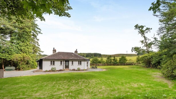 Een gelijkvloers huis met een voortuin, een kleine tuin en uitzicht op het omliggende landschap.
