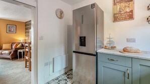 Cocina compacta con refrigerador, un reloj y un cartel en la pared.