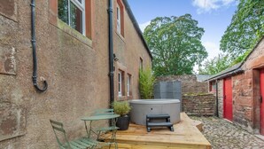 Un patio con hidromasaje, terraza de madera y mobiliario exterior.