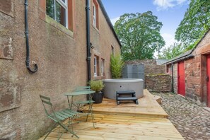 Ein Innenhof mit Whirlpool, Holzterrasse und Sitzgelegenheit im Freien.