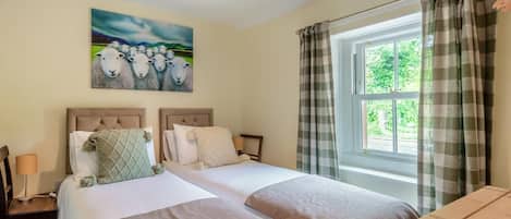 A double room with two beds, a window with curtains, a painting on the wall, and a bedside table with a lamp.
