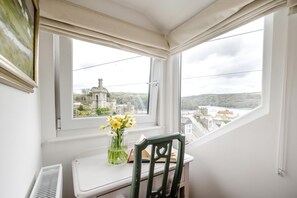 Ein Zimmer mit Blick auf ein historisches Gebäude, ein kleiner Tisch mit Stuhl und eine Vase mit Blumen.