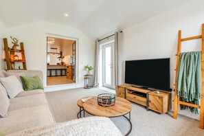 A modern living room with a sofa, a coffee table, a TV, and a wooden TV stand. - 2 Bed in Kirkby-in-Furness (oc-s42634) (Kirkby Ireleth)