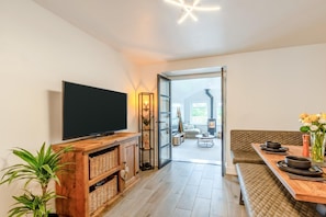 A modern living room with a television, wooden entertainment unit, and a dining area with a bench and table set for two. - 2 Bed in Kirkby-in-Furness (oc-s42634) (Kirkby Ireleth)