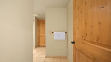 A hallway with a wooden door, a towel hanging on the wall, and a tiled floor.