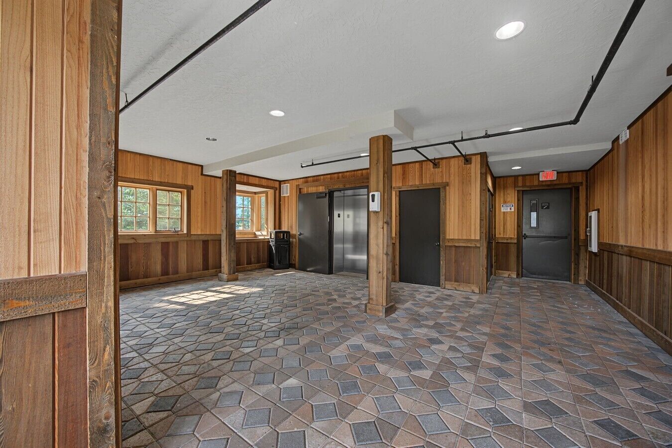A lobby with a stone-tiled floor, wooden walls, and a central column.