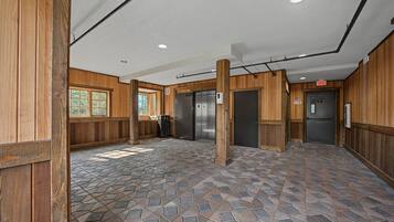 A lobby with a stone-tiled floor, wooden walls, and a central column.