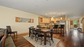 A spacious living area with a dining table, chairs, a sofa, and a kitchen in the background.