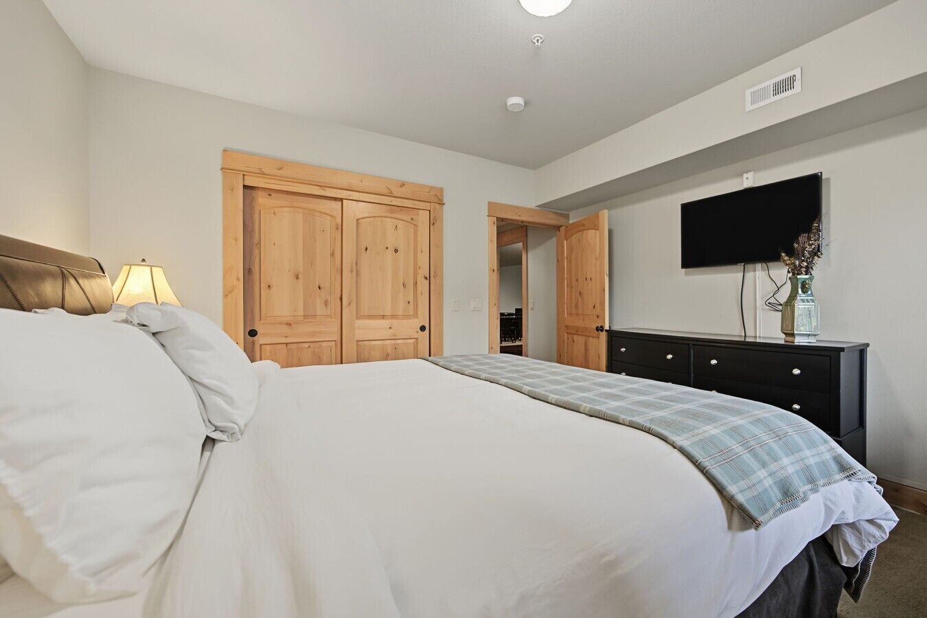 Une chambre à coucher comprenant un lit, une commode, un téléviseur et des armoires en bois.