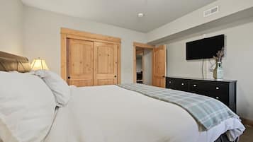 Une chambre à coucher comprenant un lit, une commode, un téléviseur et des armoires en bois.