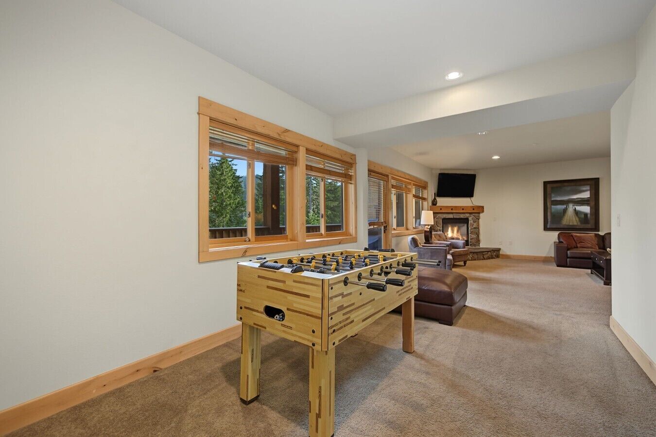 A room with a foosball table, a fireplace, a television, and a sofa.