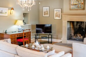 A living room with a sofa, a coffee table with tea set, a television, a fireplace, and framed pictures on the wall. - 4 Bed in Wensley (oc-t45784) (Wensley)