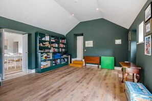 A spacious room with a wooden floor, a green bookshelf, a wooden bench, and a table with a blue box. - 4 Bed in Wensley (oc-t45784) (Wensley)