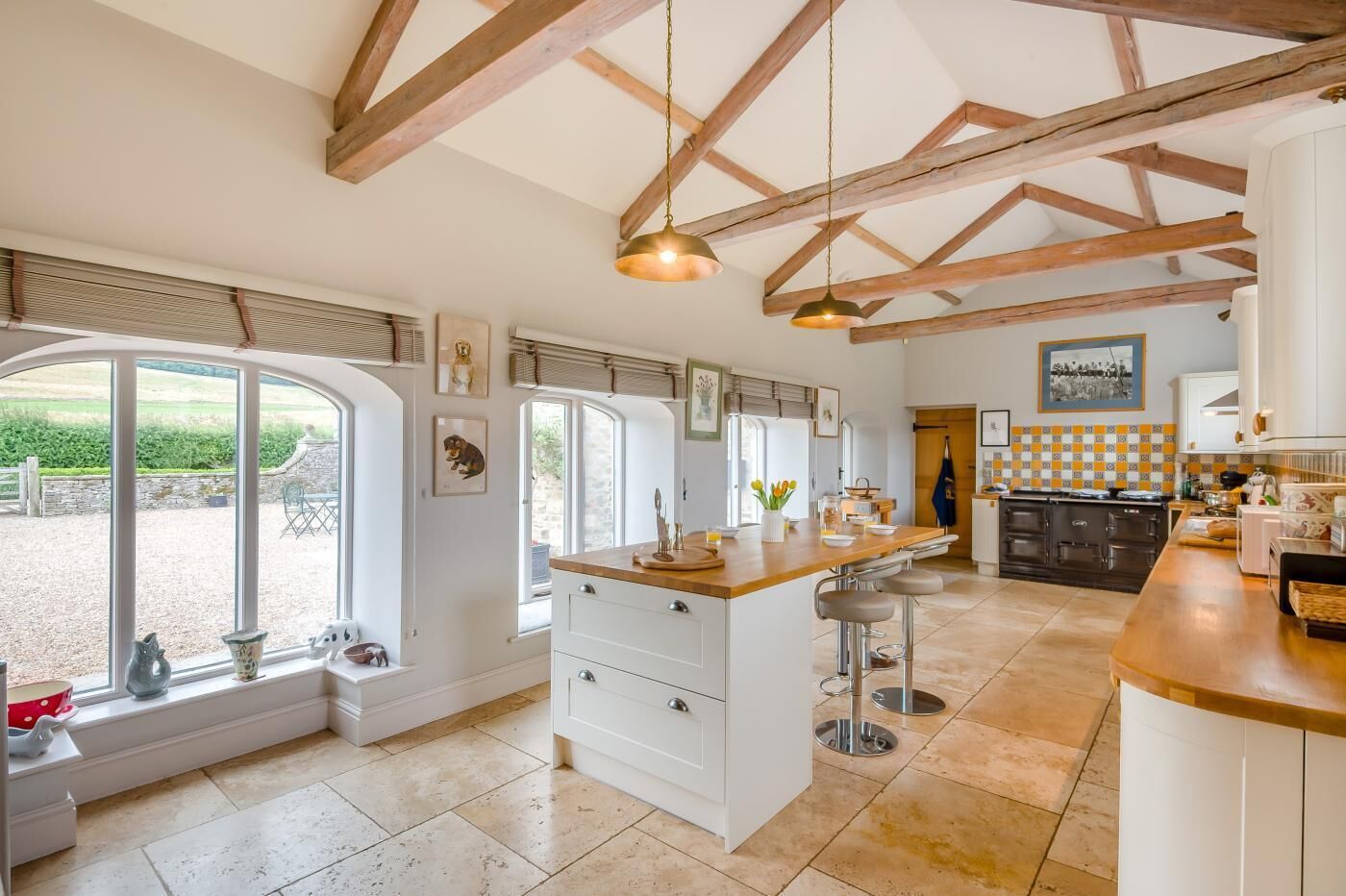 A spacious kitchen with a large island, wooden beams, and a view of the outdoors.