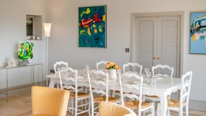 En matplats med ett vitt bord och stolar, en vas med blommor och abstrakt konst på väggarna.
